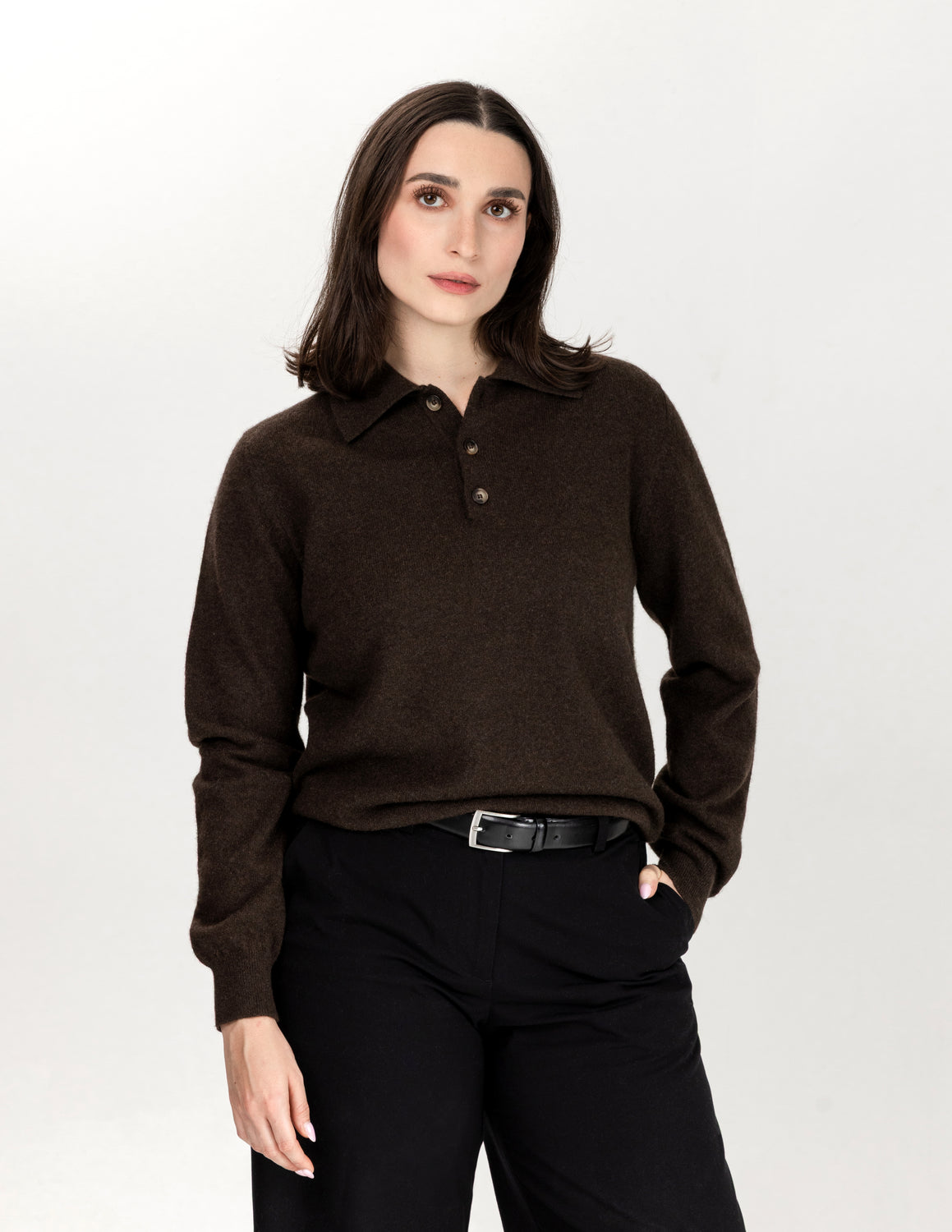 A woman modeling a dark brown long-sleeve knit polo sweater with a three-button placket, paired with black trousers and a black belt, against a plain white studio background - Natural Brown