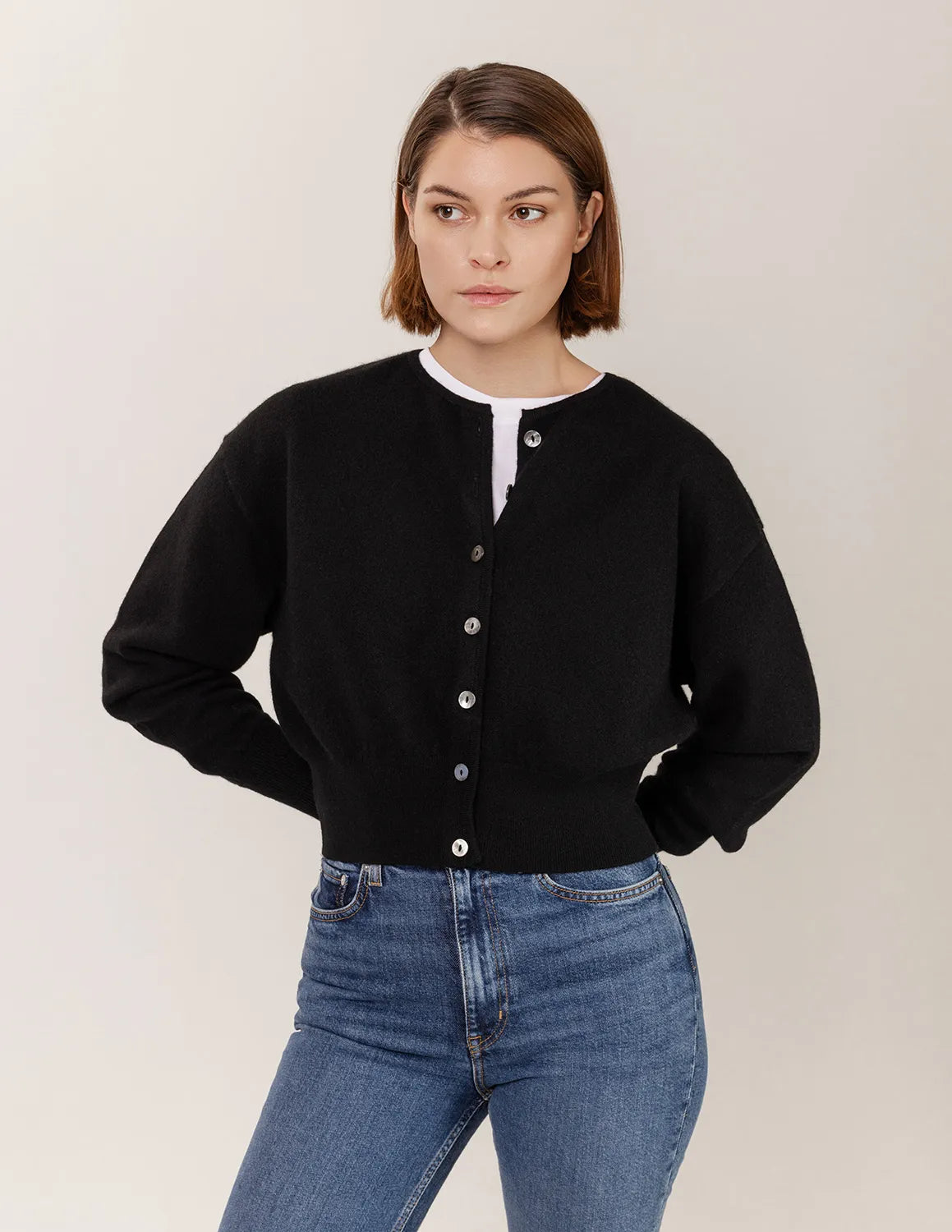 Woman wearing a black cardigan and blue jeans against a plain background - Black