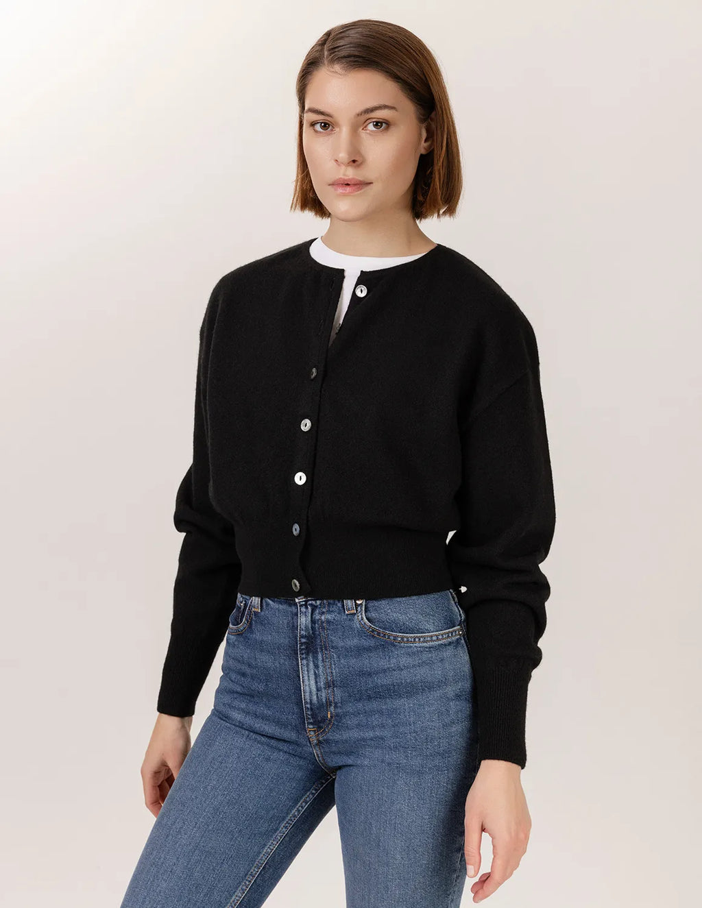 Woman wearing a black cardigan and blue jeans against a plain background - Black