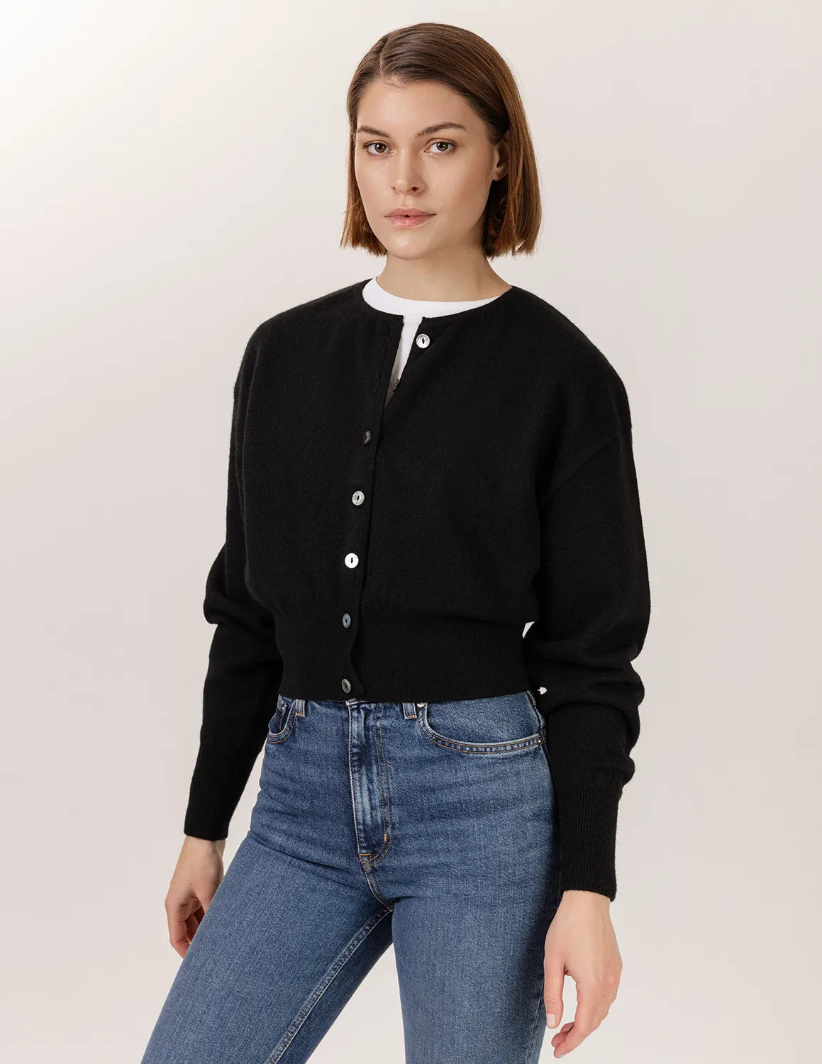 Woman wearing a black cardigan and blue jeans against a plain background - Black