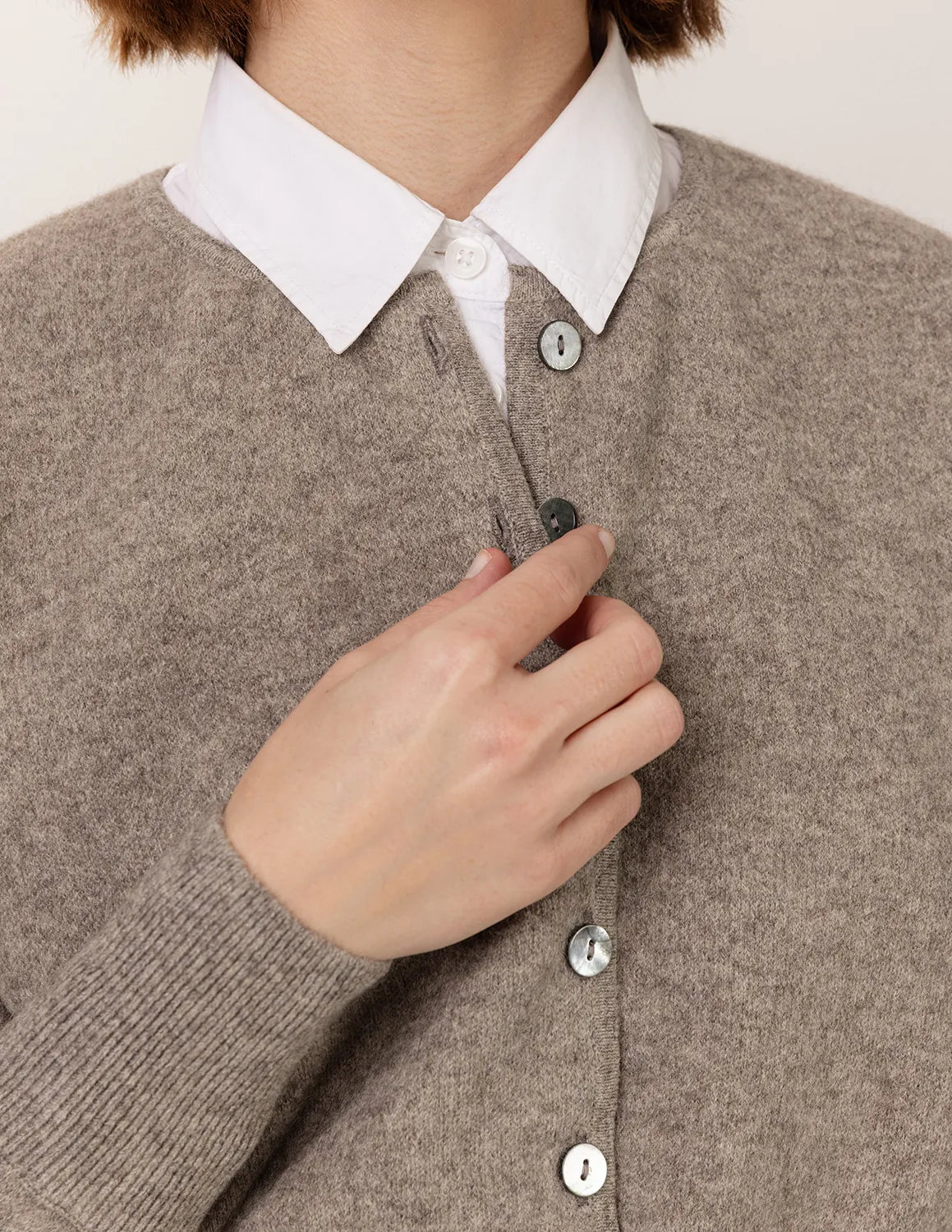 Person wearing a brown cardigan over a white shirt, buttoning it up. - Natural Grey