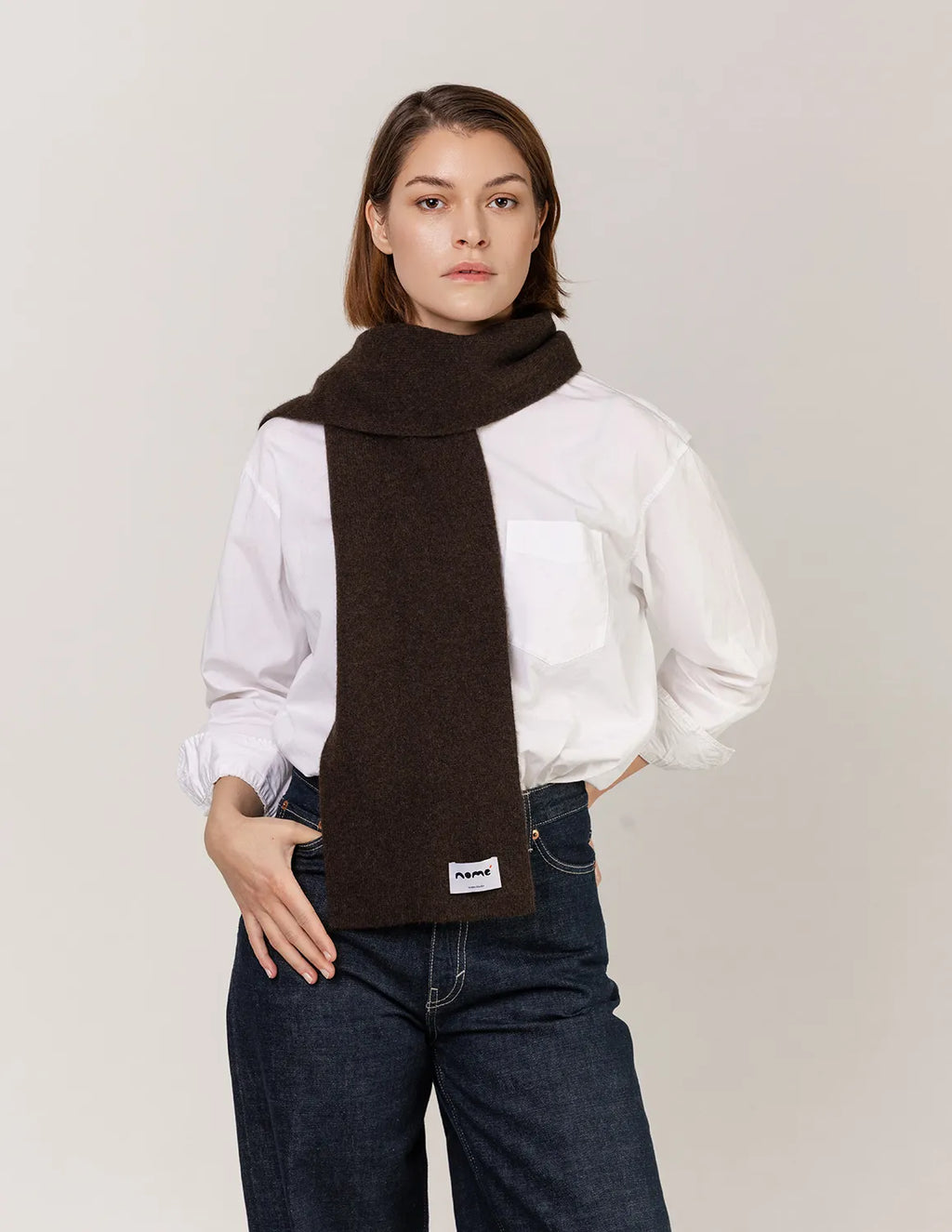 Woman wearing a brown scarf with a visible brand logo on a plain background - Natural Brown