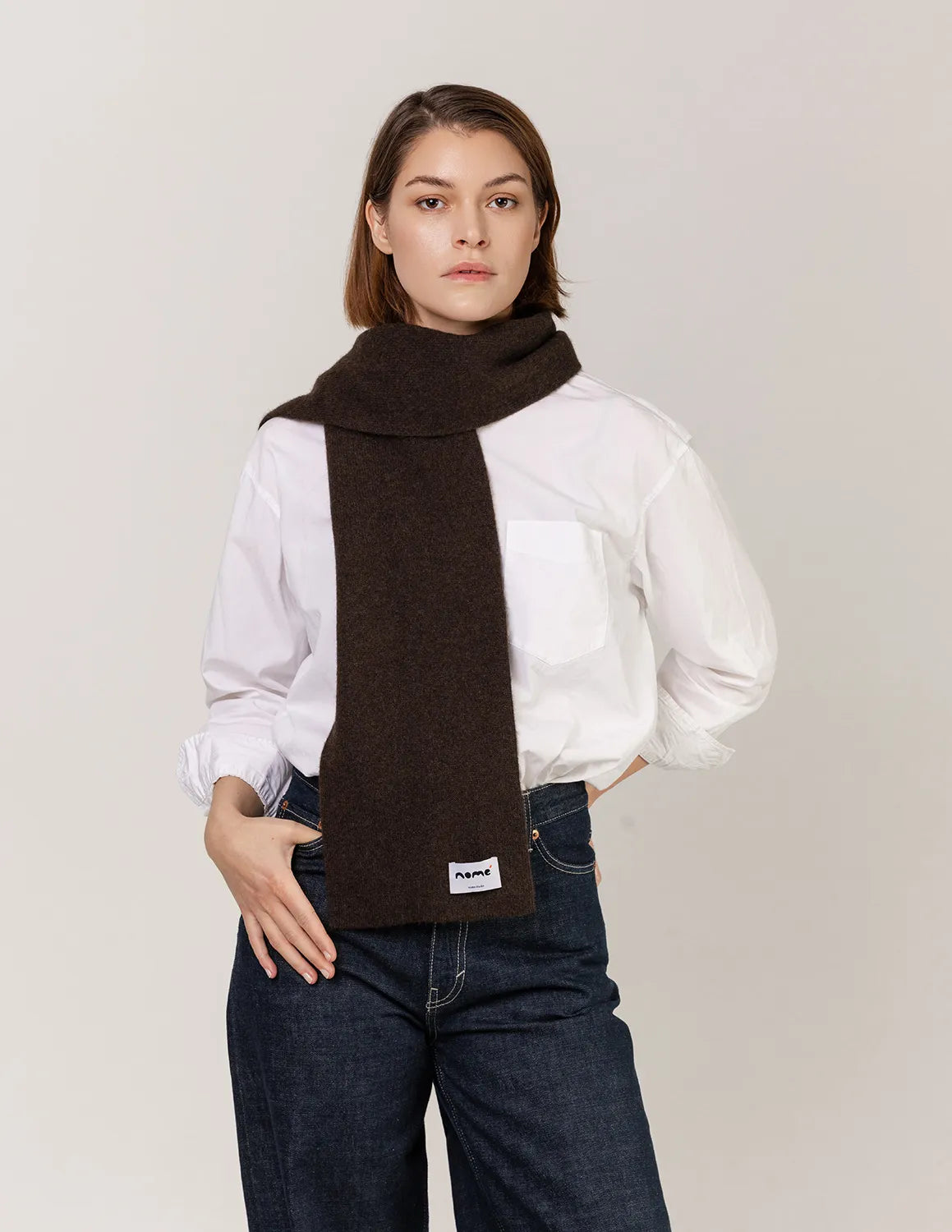 Woman wearing a brown scarf with a visible brand logo on a plain background - Natural Brown