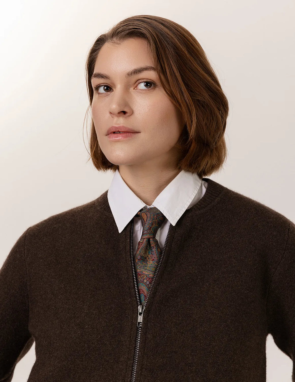 Person wearing a brown sweater over a patterned tie and white shirt against a plain background - Natural Brown