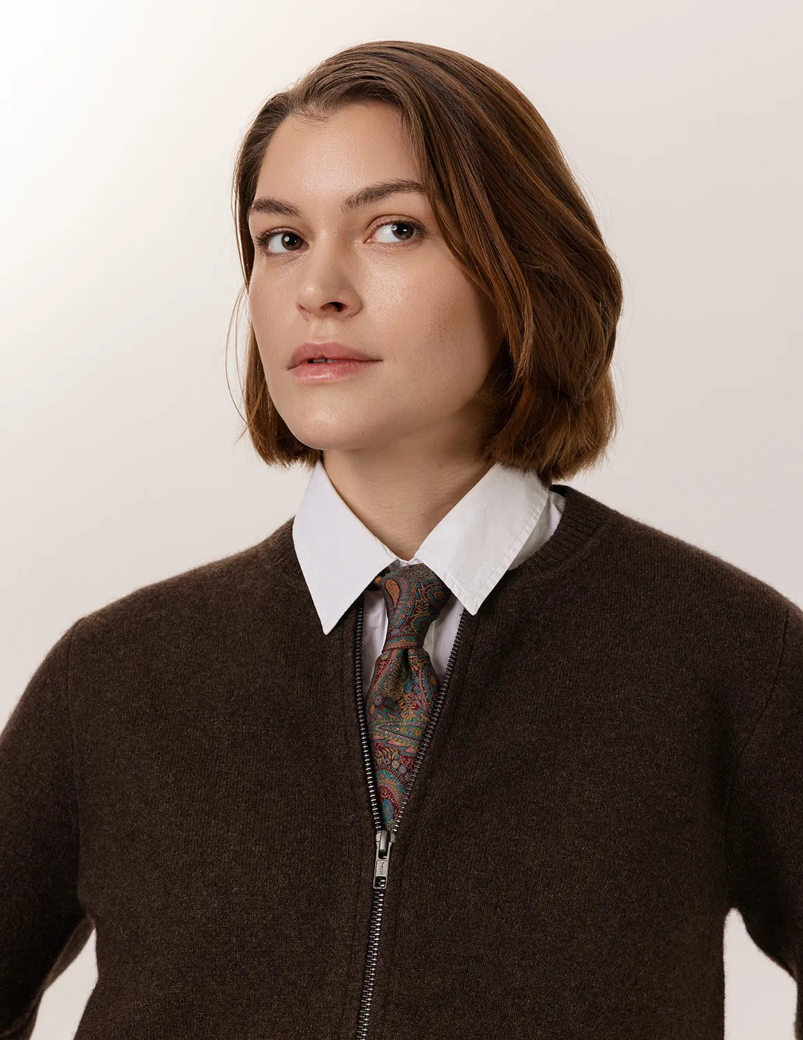 Person wearing a brown sweater over a patterned tie and white shirt against a plain background - Natural Brown
