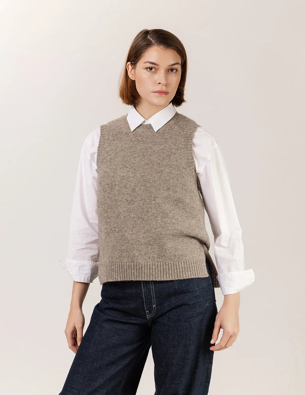 Woman wearing a brown knitted vest over a white shirt with a plain background - Natural Grey