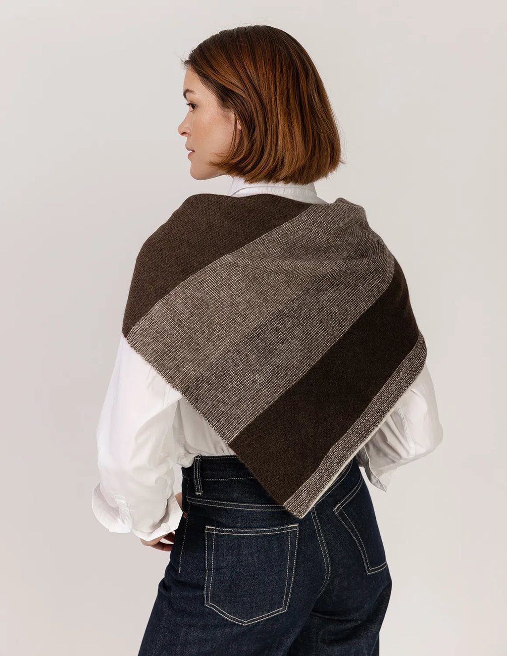 Woman wearing a brown and gray striped shawl on a plain background
