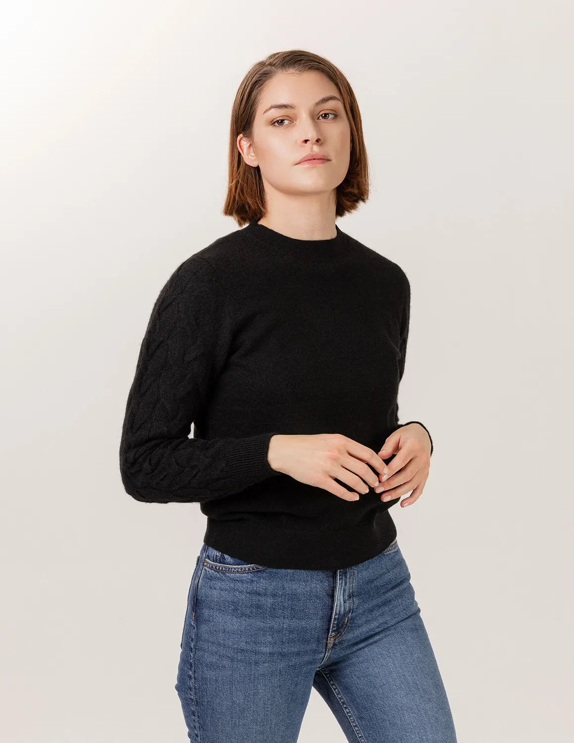 Woman wearing a black sweater and blue jeans against a white background - Black