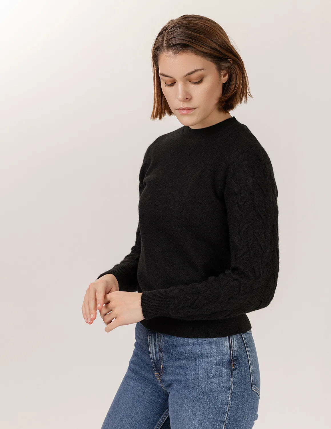 Person wearing a black sweater and blue jeans on a light background - Black