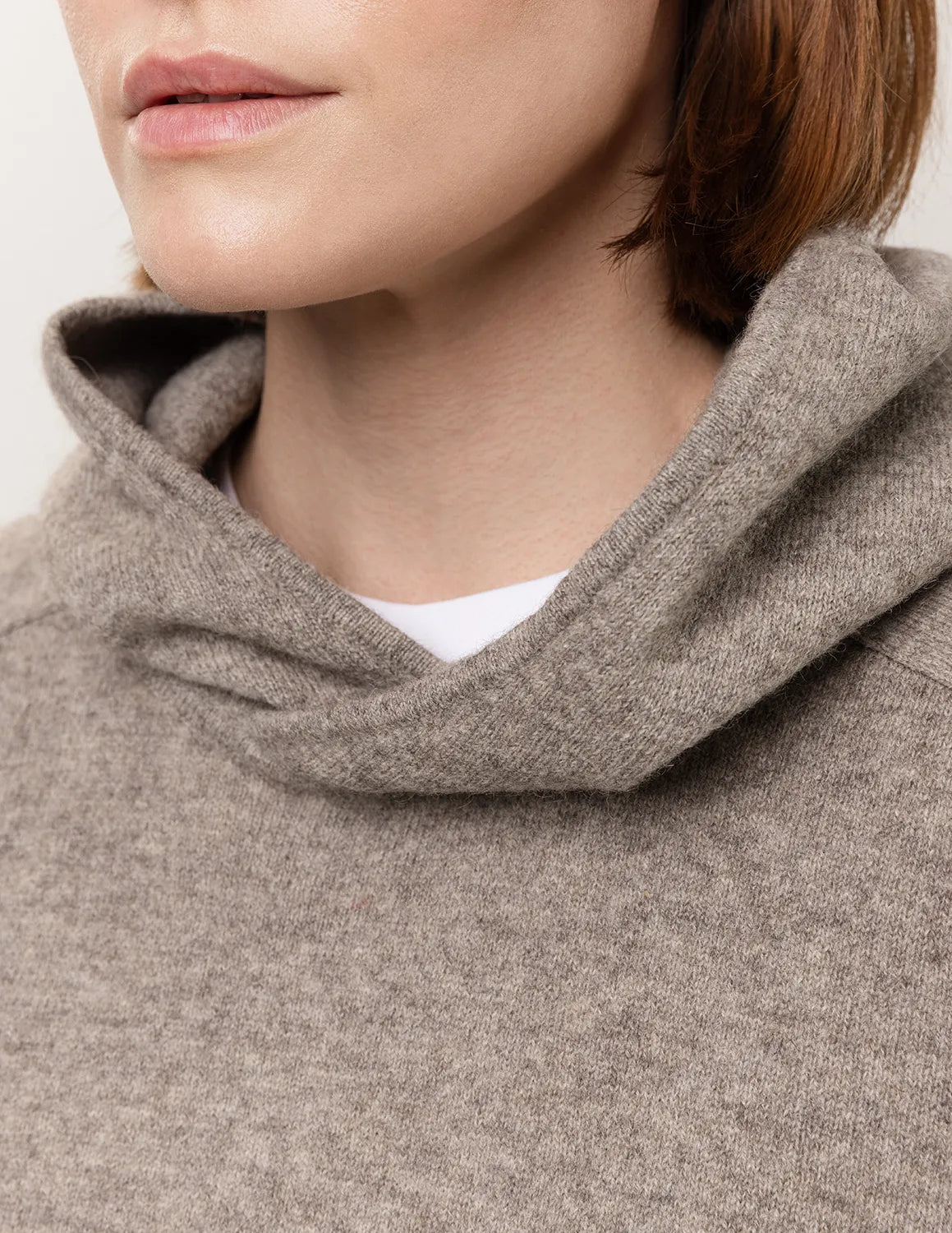 Close-up of a person wearing a brown hooded garment with a neutral background - Natural Grey