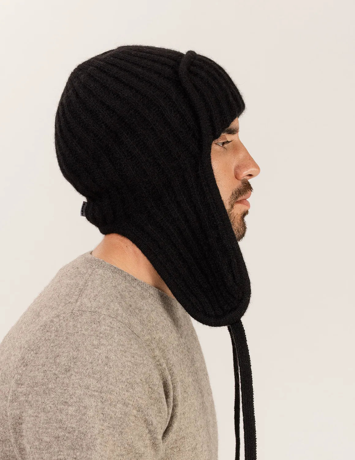 Man wearing a black knitted hood over his head against a plain background - Black