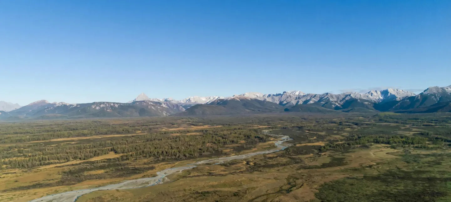 Panoramic view of a valley with mountains in the distance under a clear blue sky.