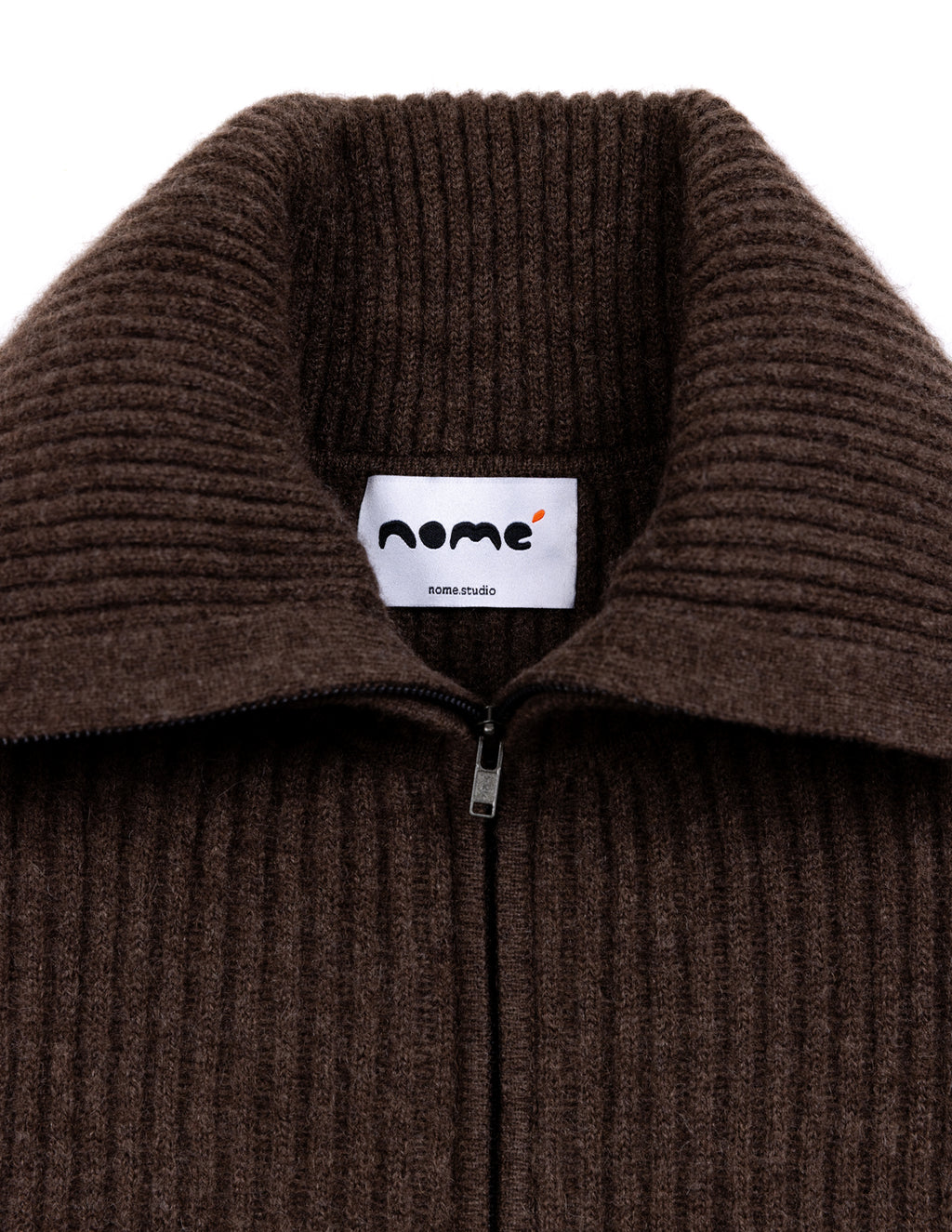 Close-up of a dark brown ribbed knit zip-up sweater collar with a white inner label reading 'nome' and 'nome studio'. - Natural Brown