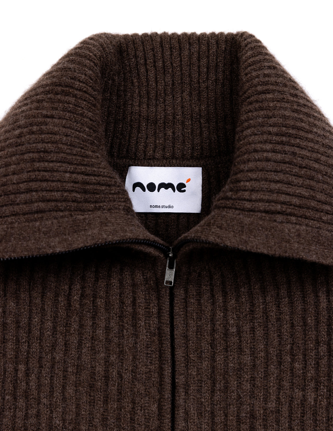 Close-up of a dark brown ribbed knit zip-up sweater collar with a white inner label reading 'nome' and 'nome studio'. - Natural Brown